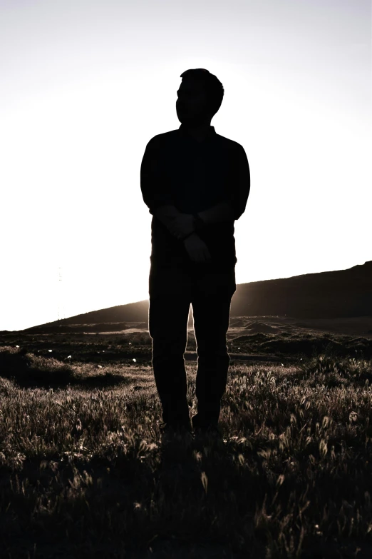 the person is standing in an open field with his arms crossed