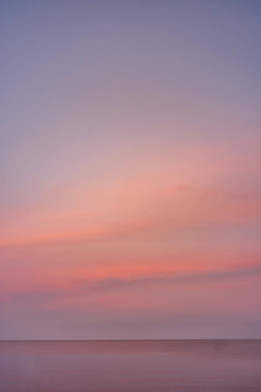 a hazy sky and the silhouette of two people in an ocean with boats