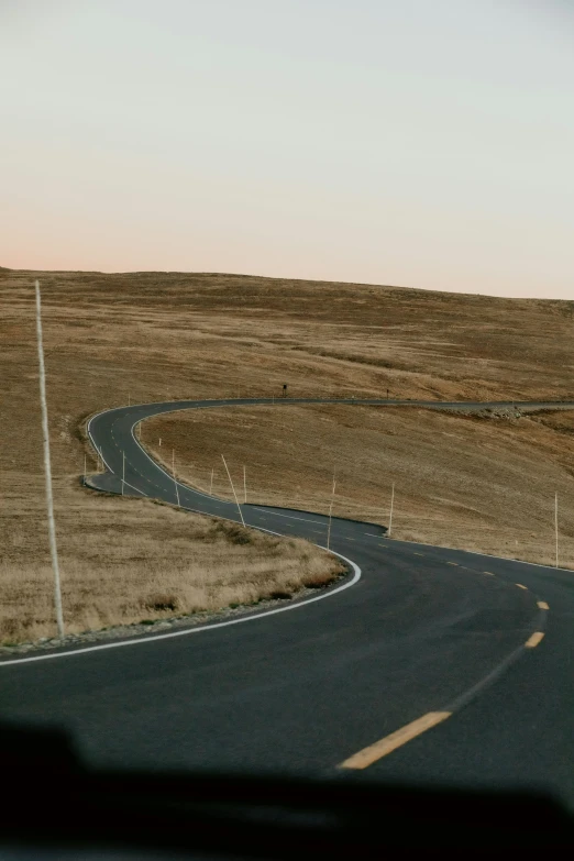 an empty winding road in the middle of a plain
