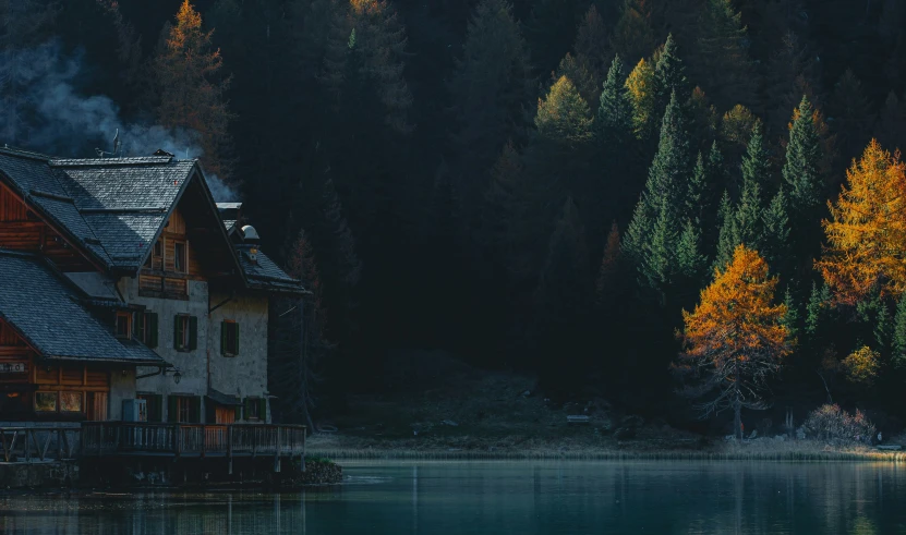 a house sits beside a small lake surrounded by woods