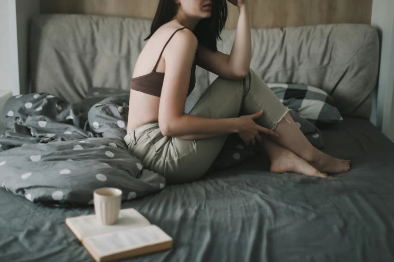 a woman sits on a bed, while using her cell phone