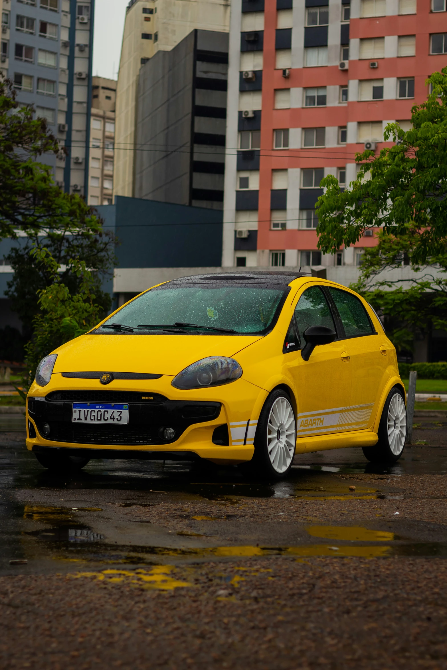 this small yellow car is parked in the rain