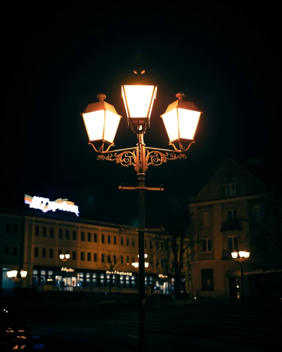 a street lamp at night on a pole with three lamps on top