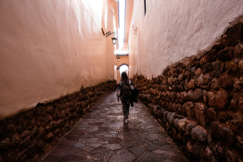 woman walking down a narrow stone - paved alley way