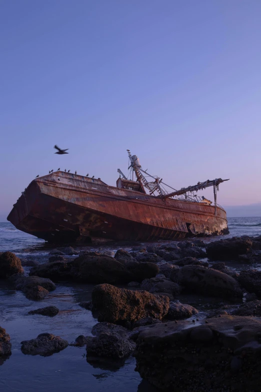 a wooden ship sits on rocks in the water