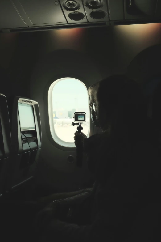 a man taking pictures through a window on an airplane