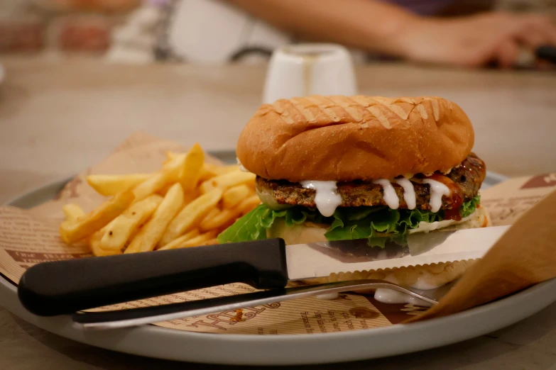 a hamburger and fries on a paper tray with a knife and fork