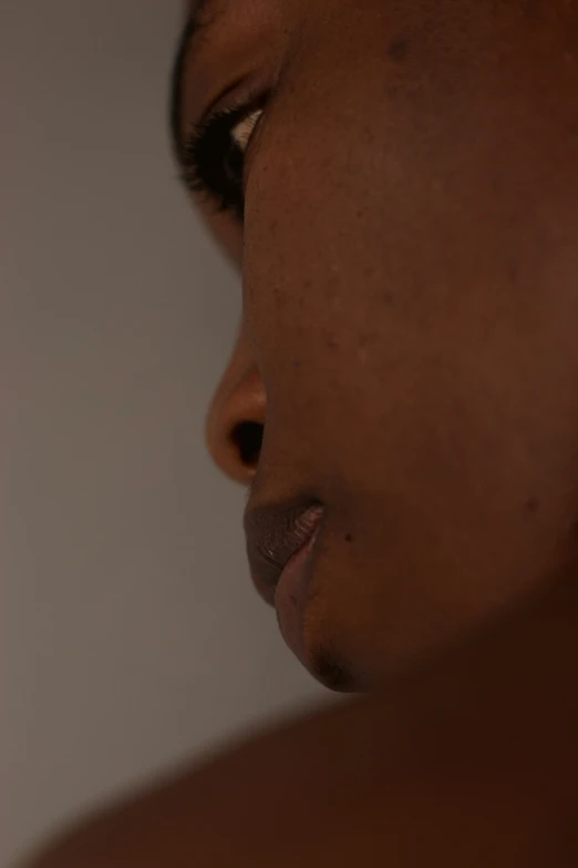 a woman with black makeup looks down while holding an object