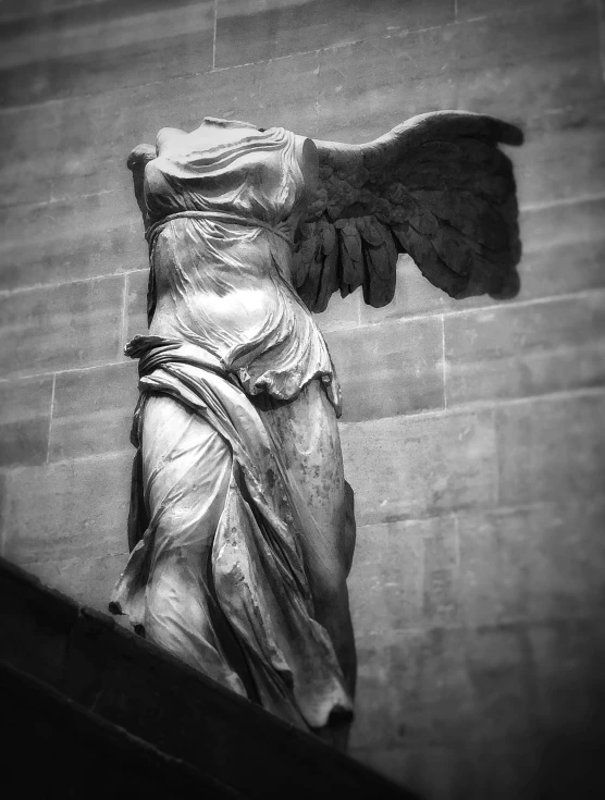 black and white pograph of angel statue in front of wall