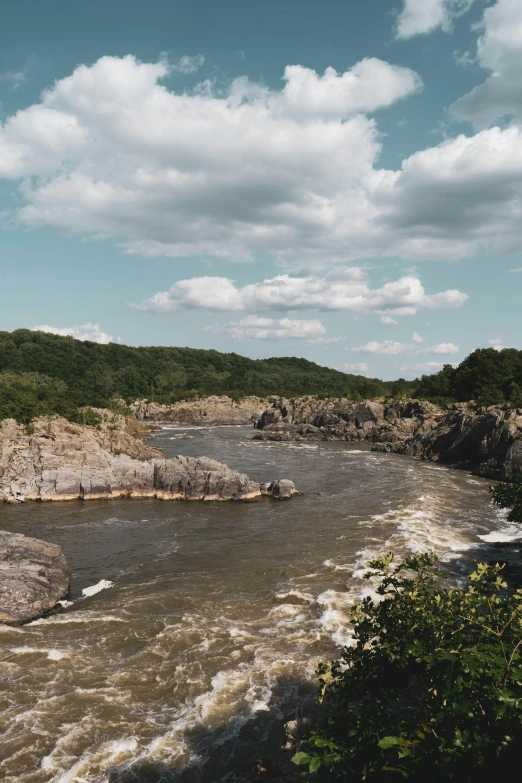 a river running along side of a lush green hillside