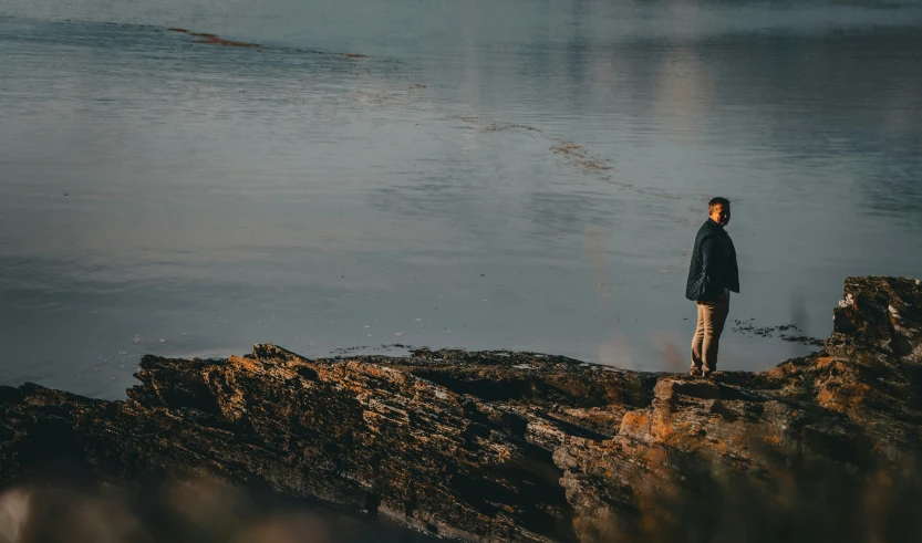 a man standing on rocks overlooking a body of water