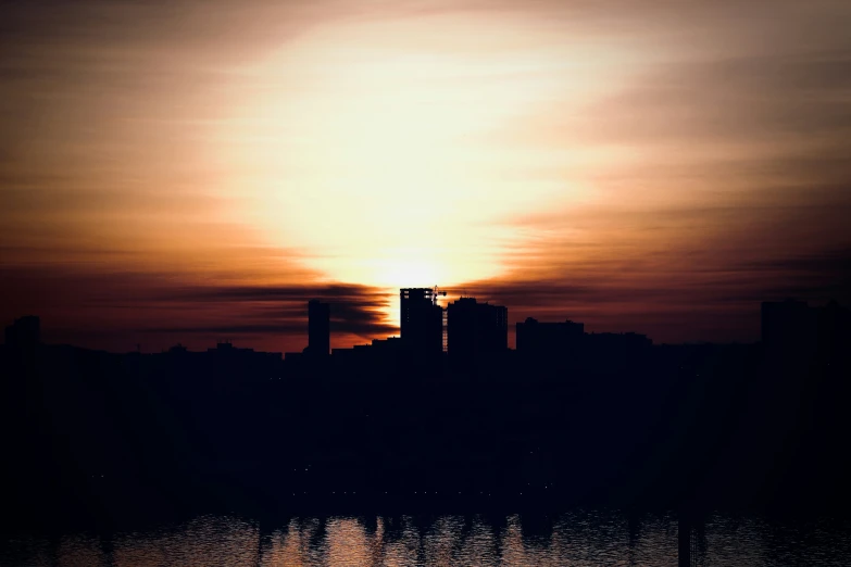 a view of the sun over the city of tall buildings