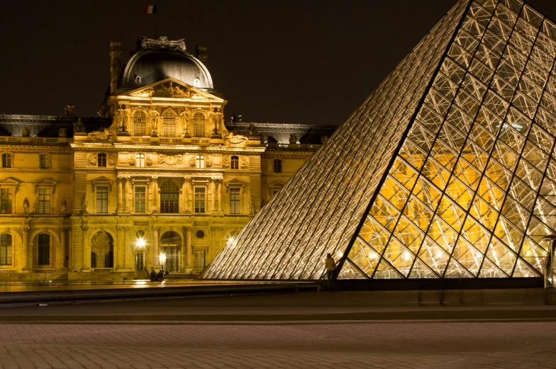 a pyramid and another building are illuminated in yellow