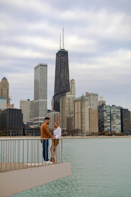 two people standing on the ledge of a bridge over a body of water