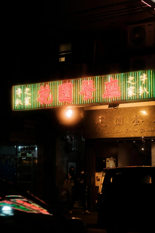 a sign lit up over a city street in an asian language