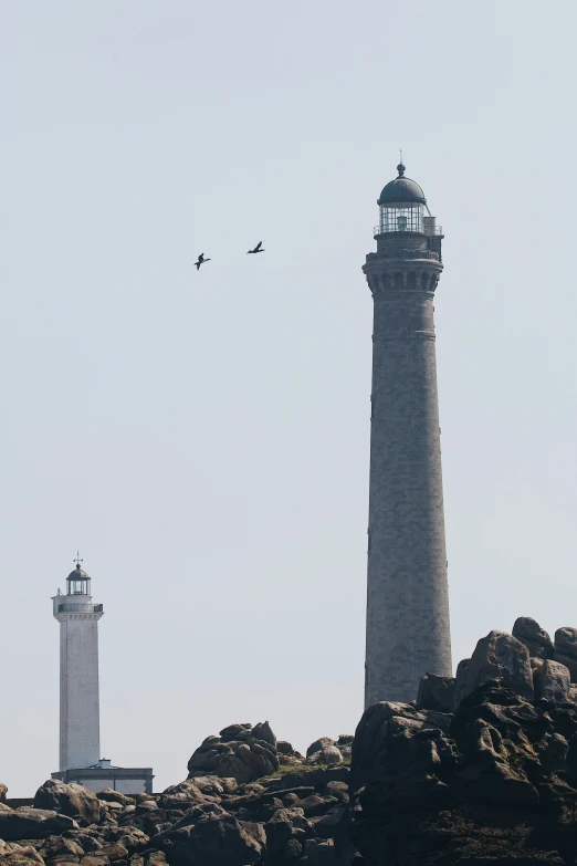 the two large lighthouses are standing on top of some rocks