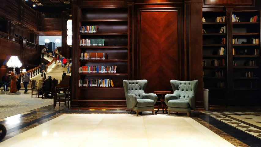 the two blue chairs are in front of the bookshelves