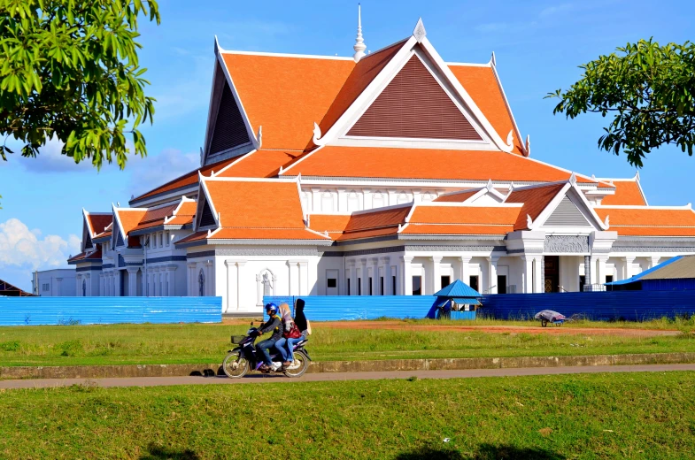 two people on motor bikes pass a large white building