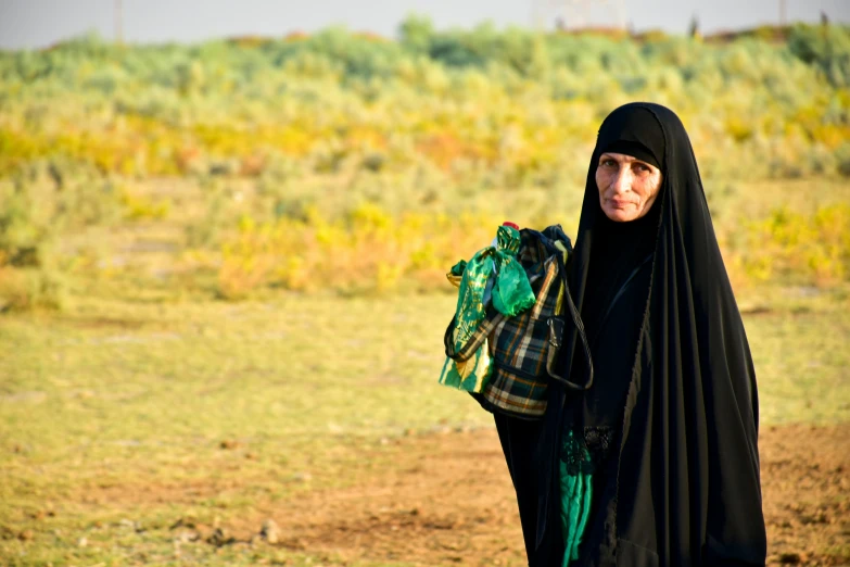 a woman wearing a black shawl is holding a green purse