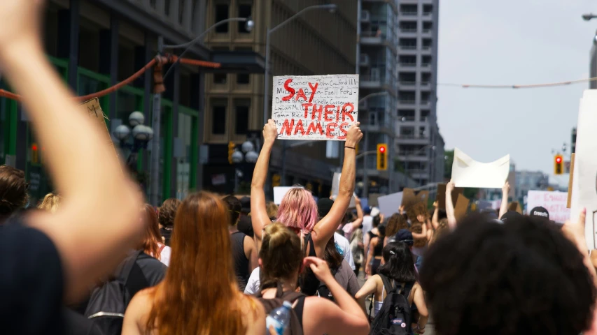 some people with signs on the street and one holding up a cell phone