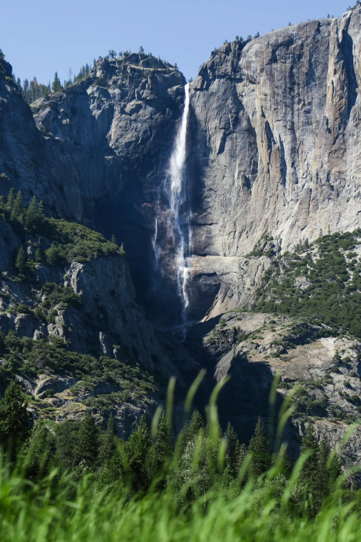 a mountain top with a waterfall surrounded by lush green trees