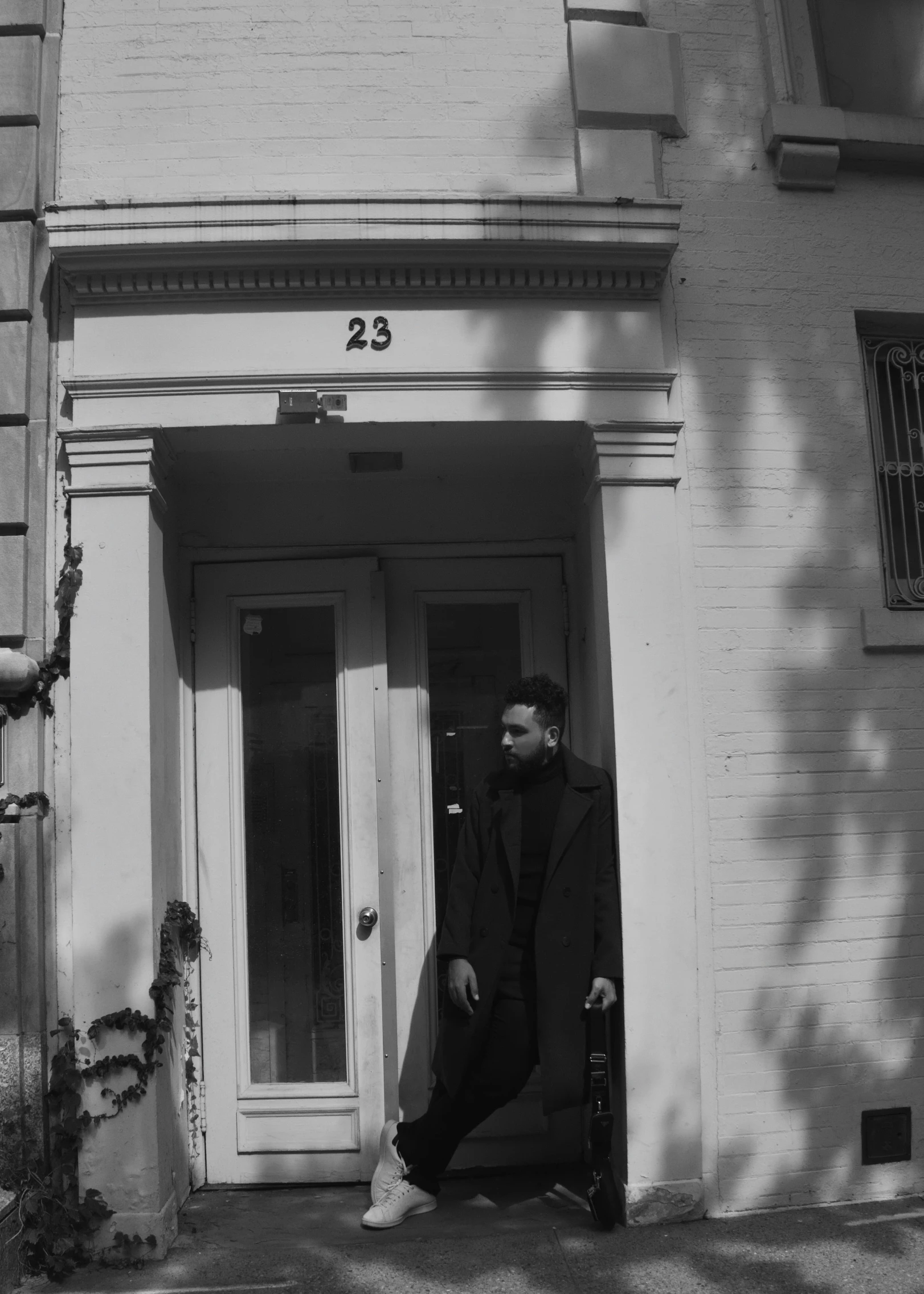 black and white pograph of man standing by entrance