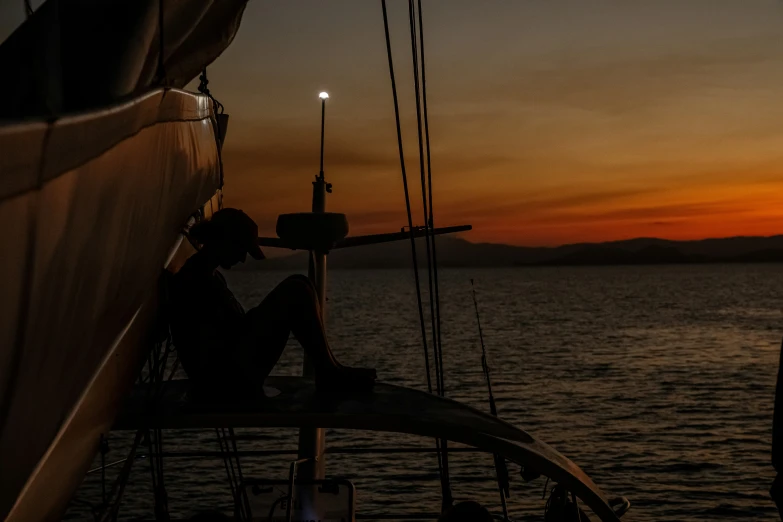 the silhouette of a person on a boat, during the sunset