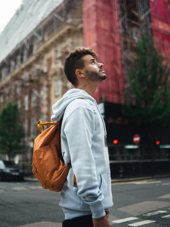 a young man crossing a street with a backpack