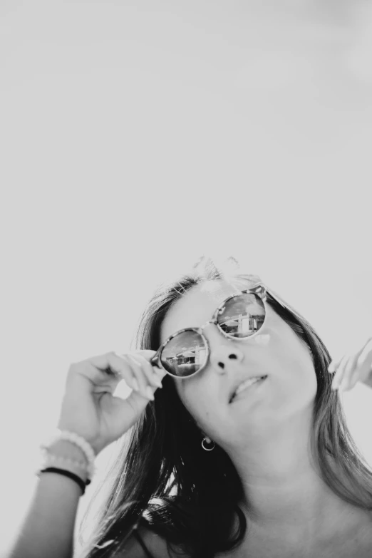 a young woman adjusts her sun glasses