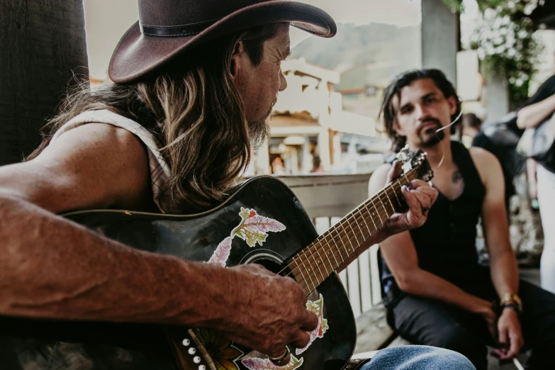 a man in cowboy hat playing guitar on steps