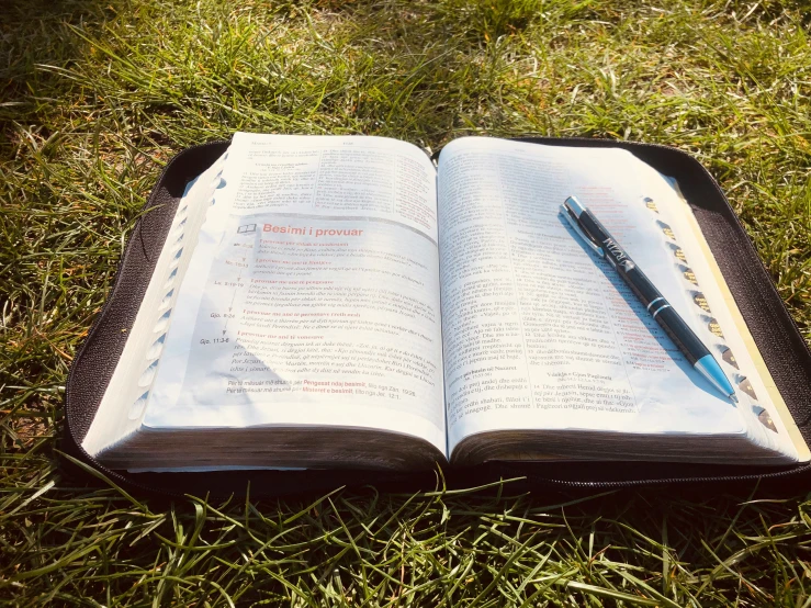 an open book sitting on top of grass