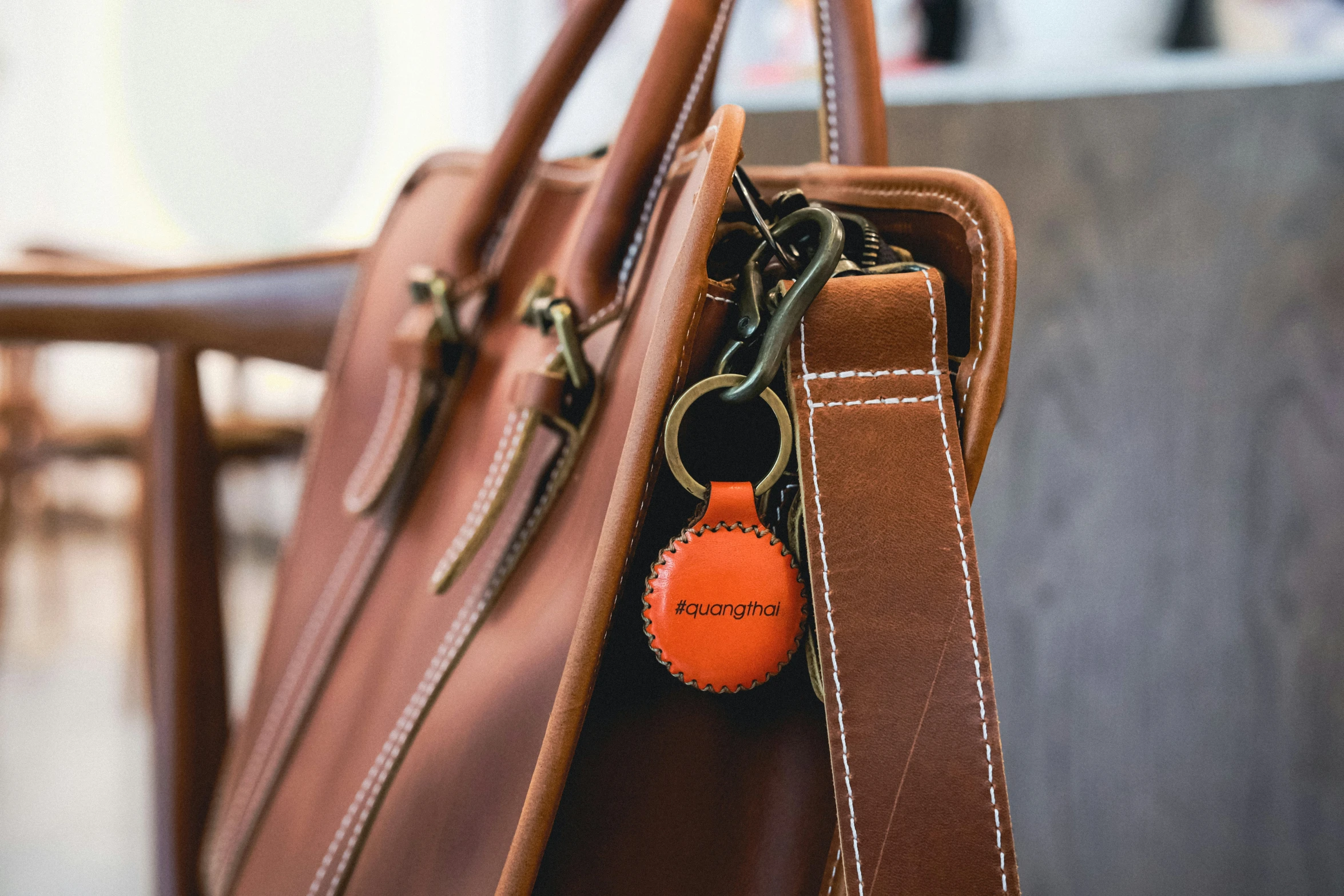 a tan leather purse with two orange colored ons