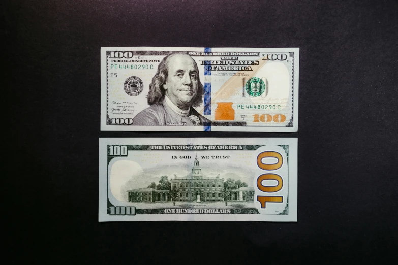 two bills of paper money on a black surface