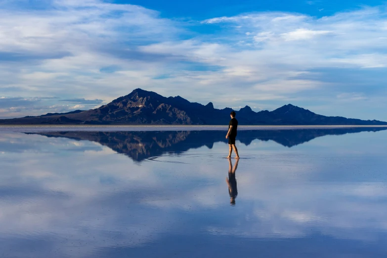 a person standing in front of a large lake with mountains in the background