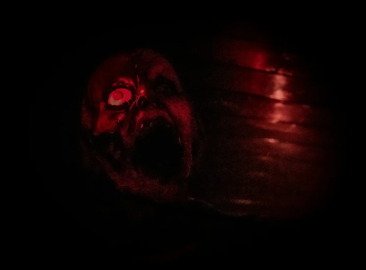 an open mouth with red eyes in the darkness