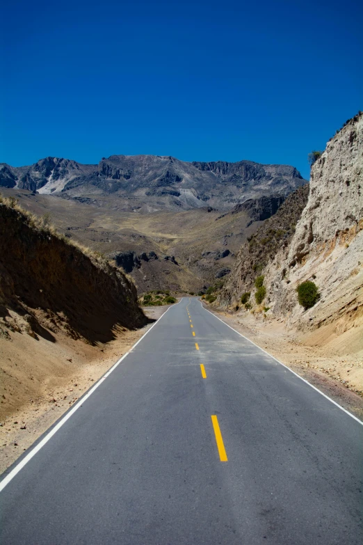 a long road is lined with mountains near the desert