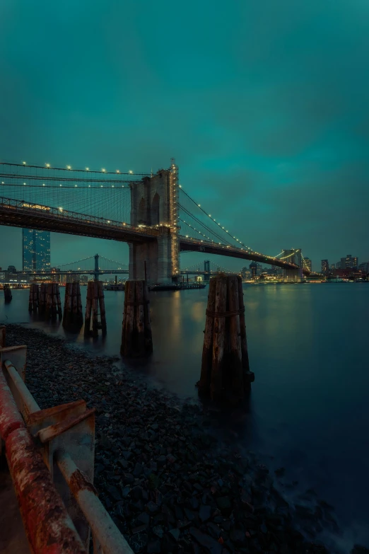 a bridge with water below and city lights over it