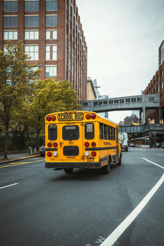 a school bus rides through the streets with pedestrians