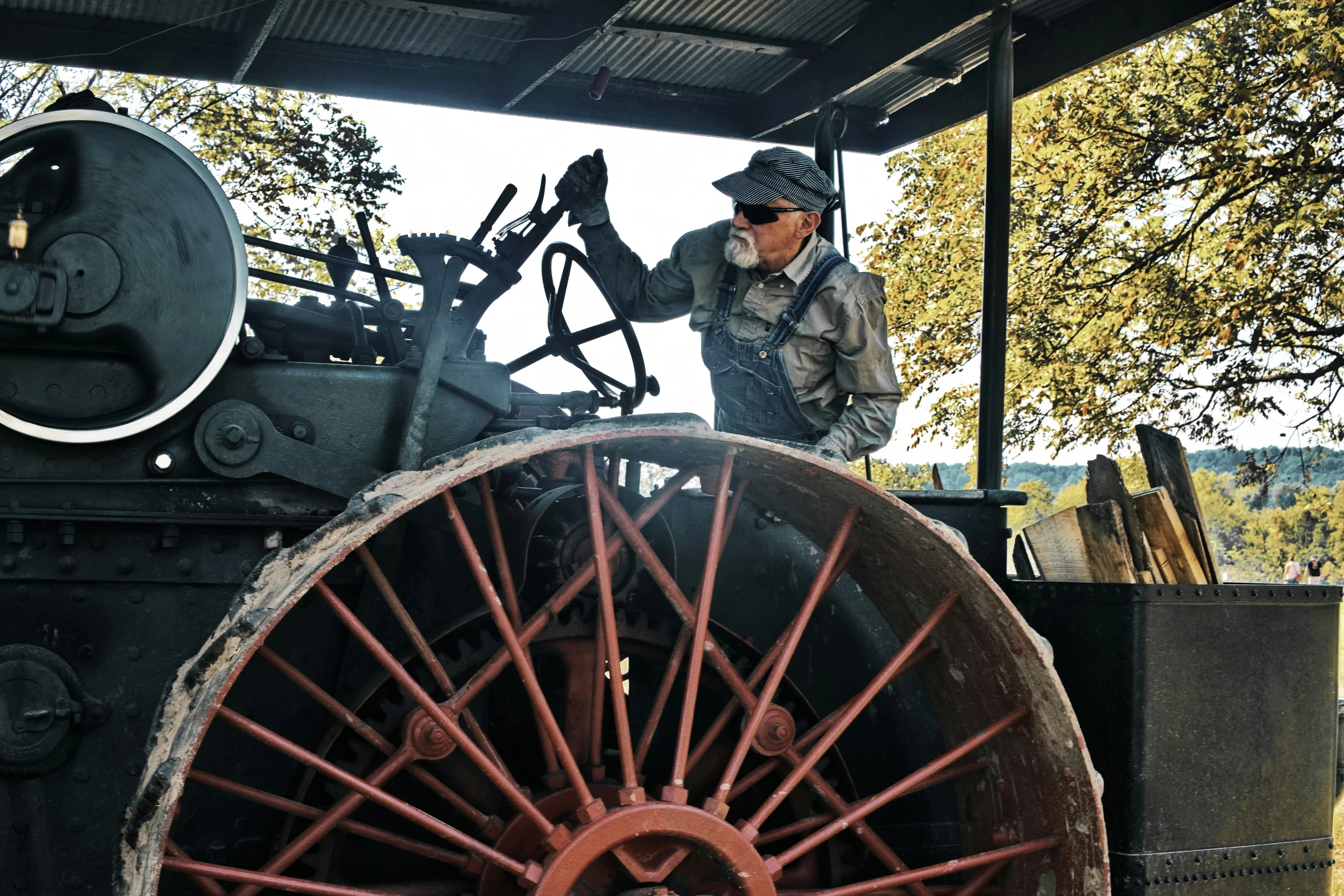 man in a helmet standing next to an old rusty tractor