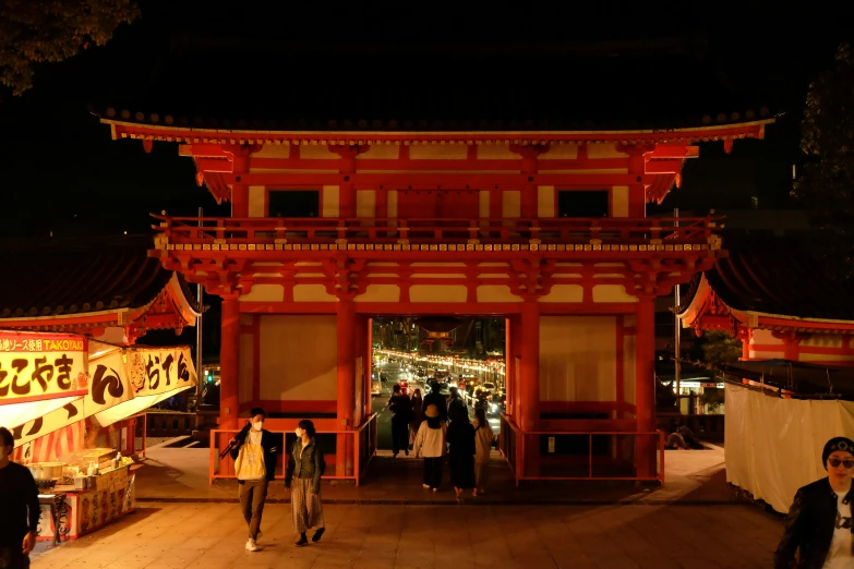 people walking around in front of a building at night