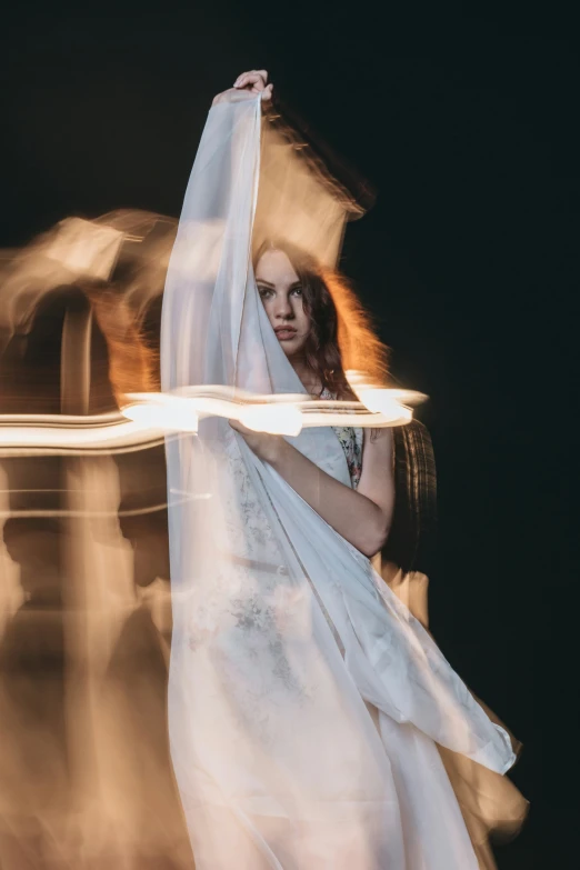 a woman holding her long wedding dress up while staring at the camera