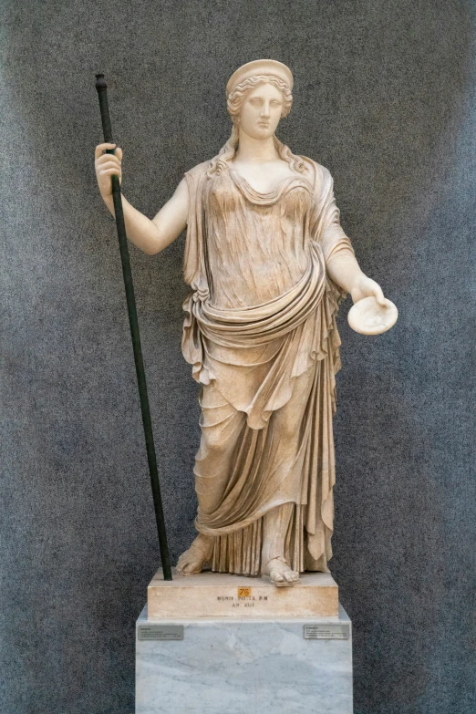 a statue with a hat and staff stands on display