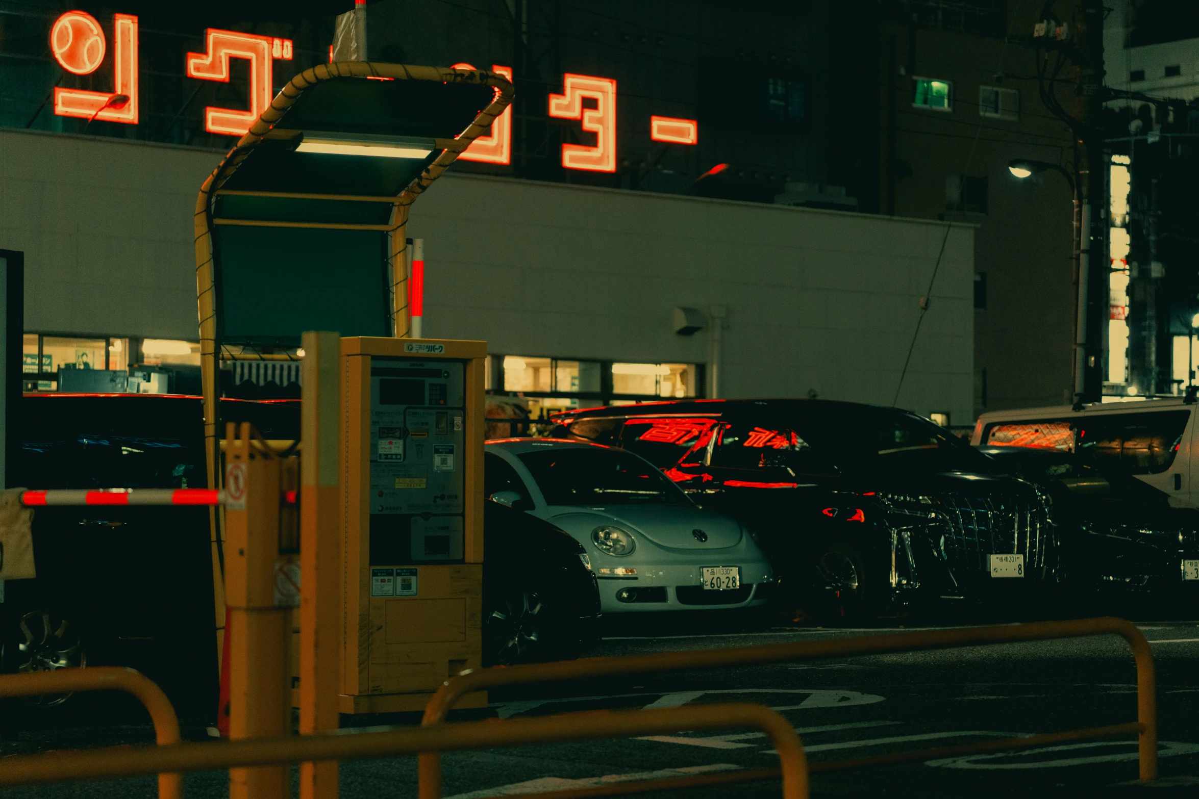 a city street with parked cars and large neon sign