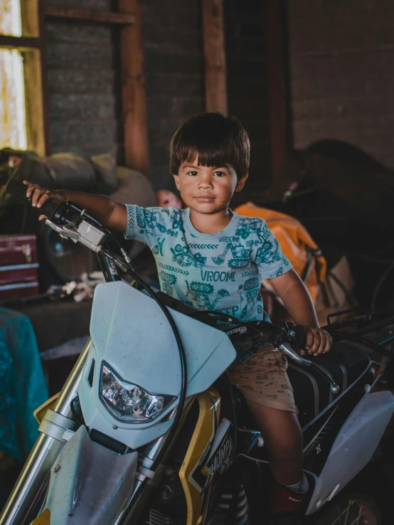 small boy sits on motorcycle inside an abandoned warehouse