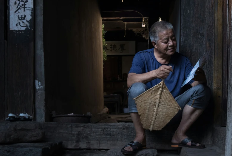 an old man holding up a basket to his face