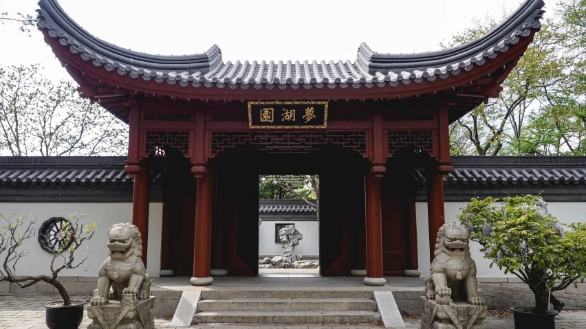 a large wooden and tile building with a gate and statues in front of it