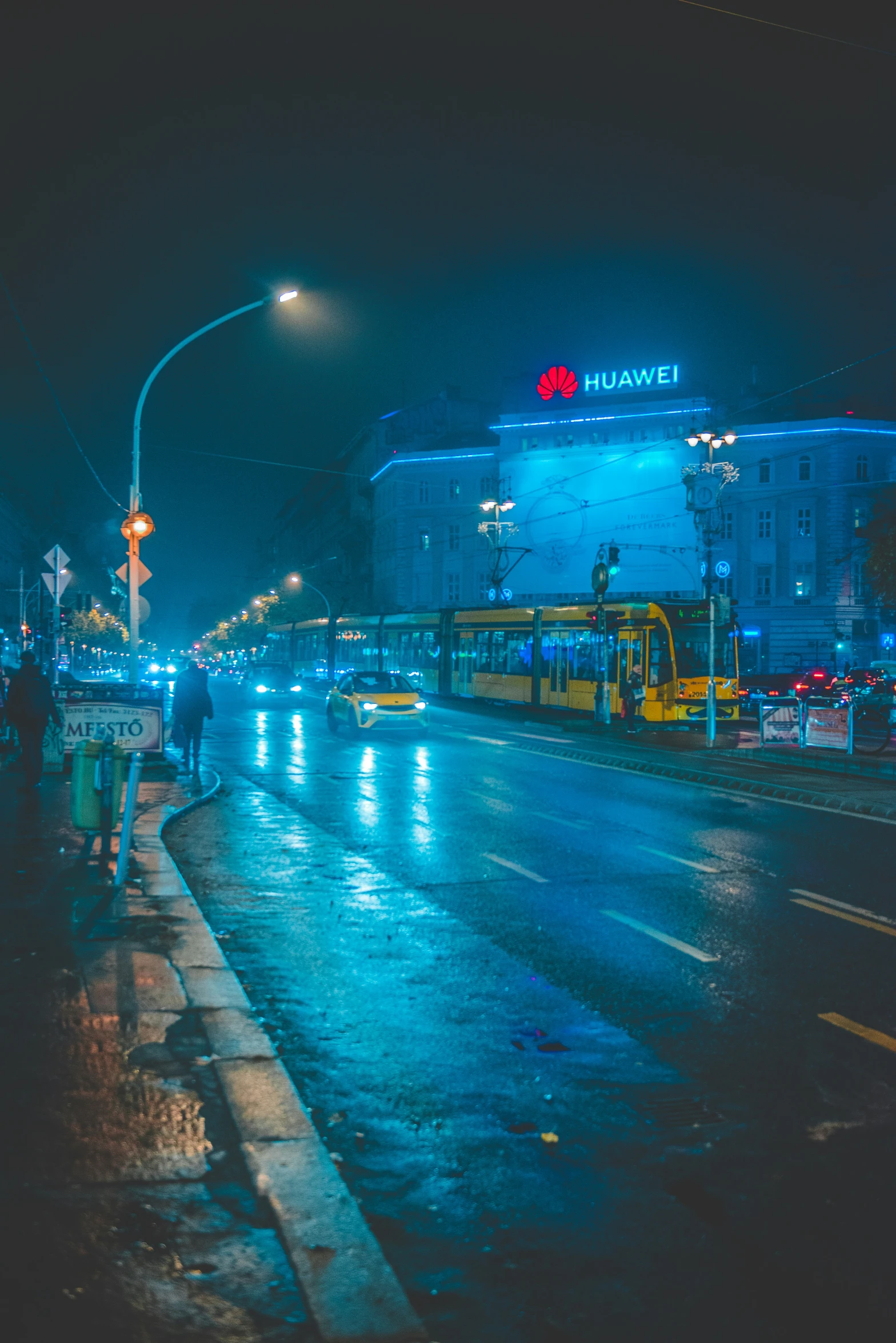 a light rail crossing the street in the rain