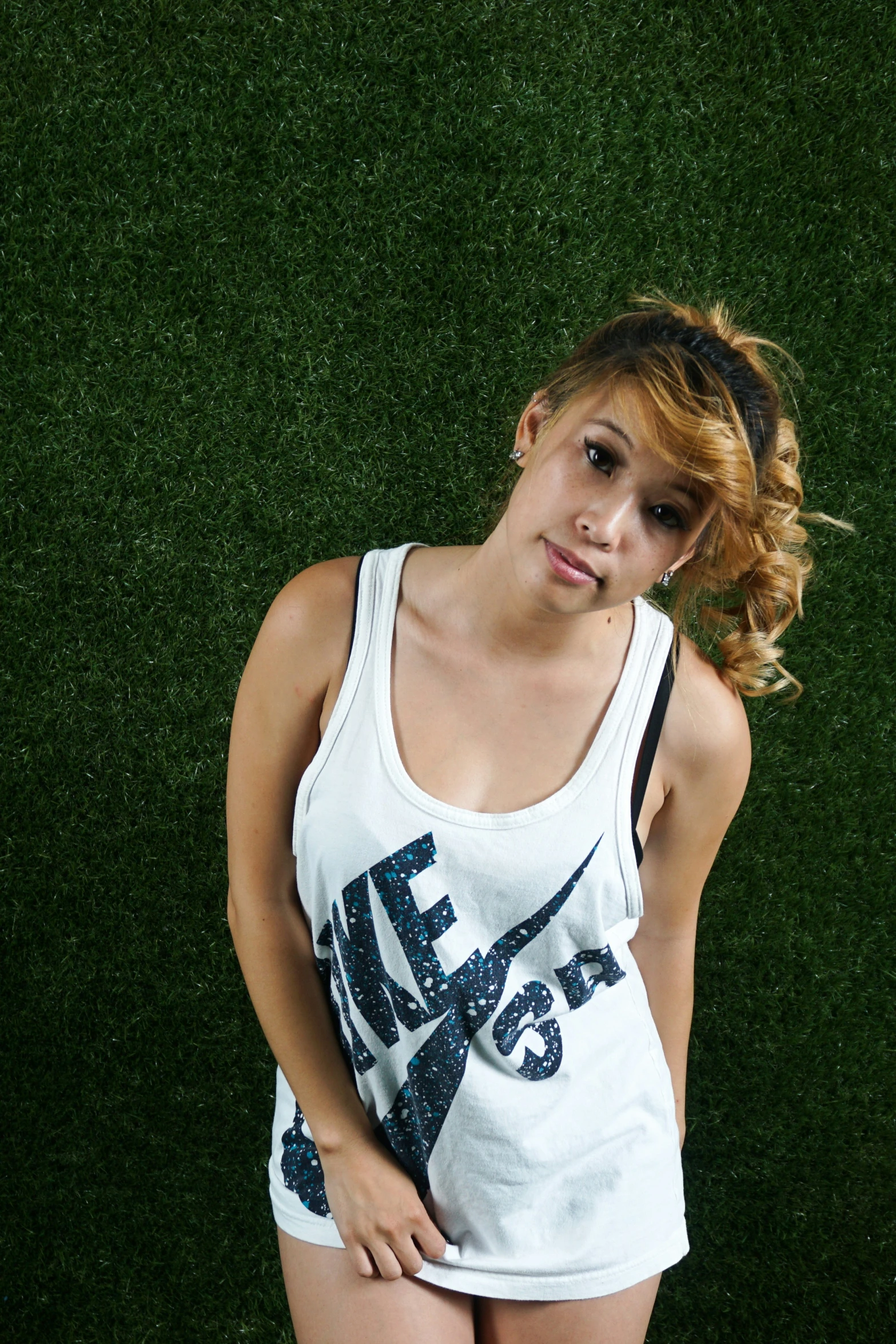 a young woman standing in front of a grassy wall