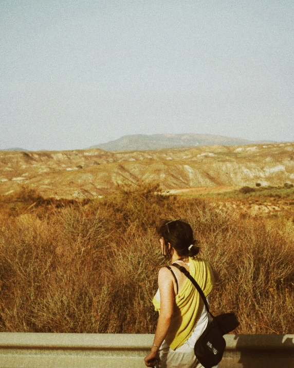 a woman is standing behind a wall by an open field