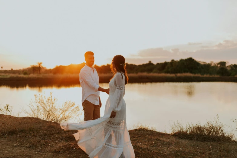 couple dancing near body of water at sunset